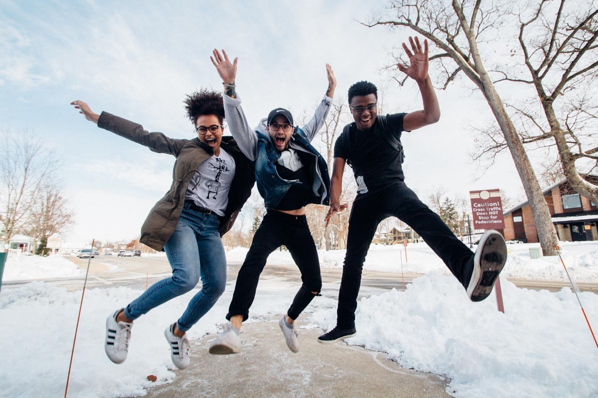 Three youth jumping up in the air happily.