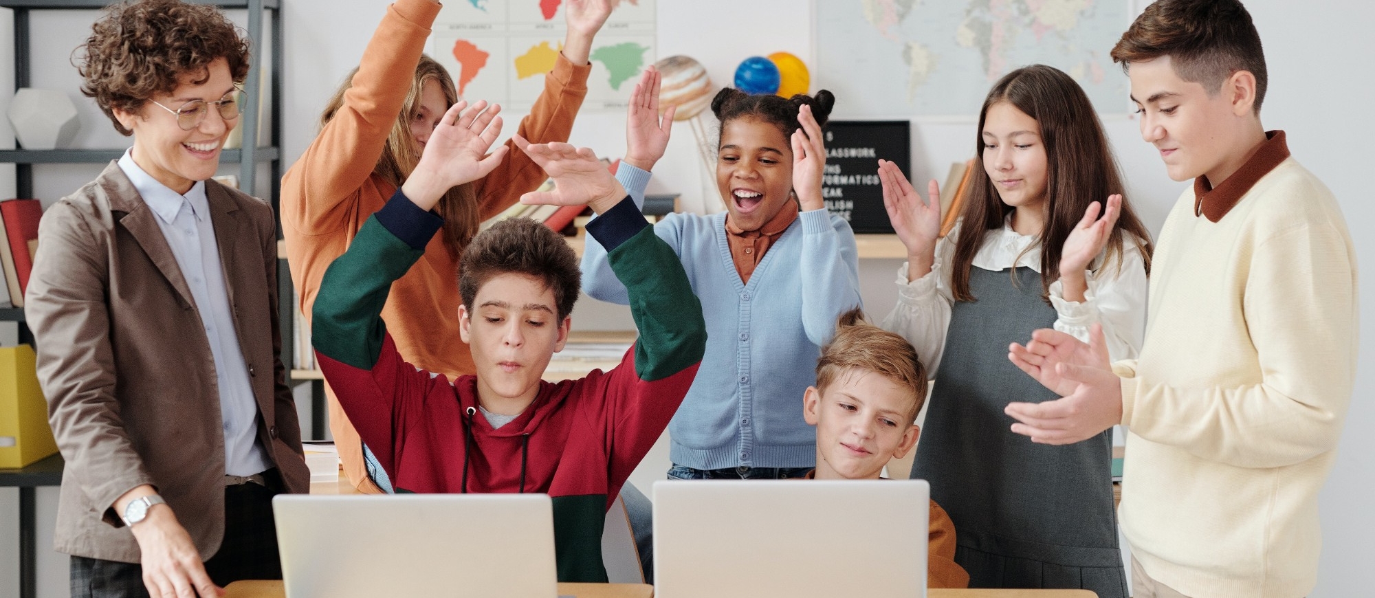 Students raising hands happily in a classroom