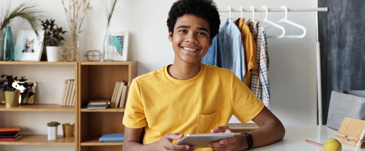 Teenager smiling at camera holding an ipad