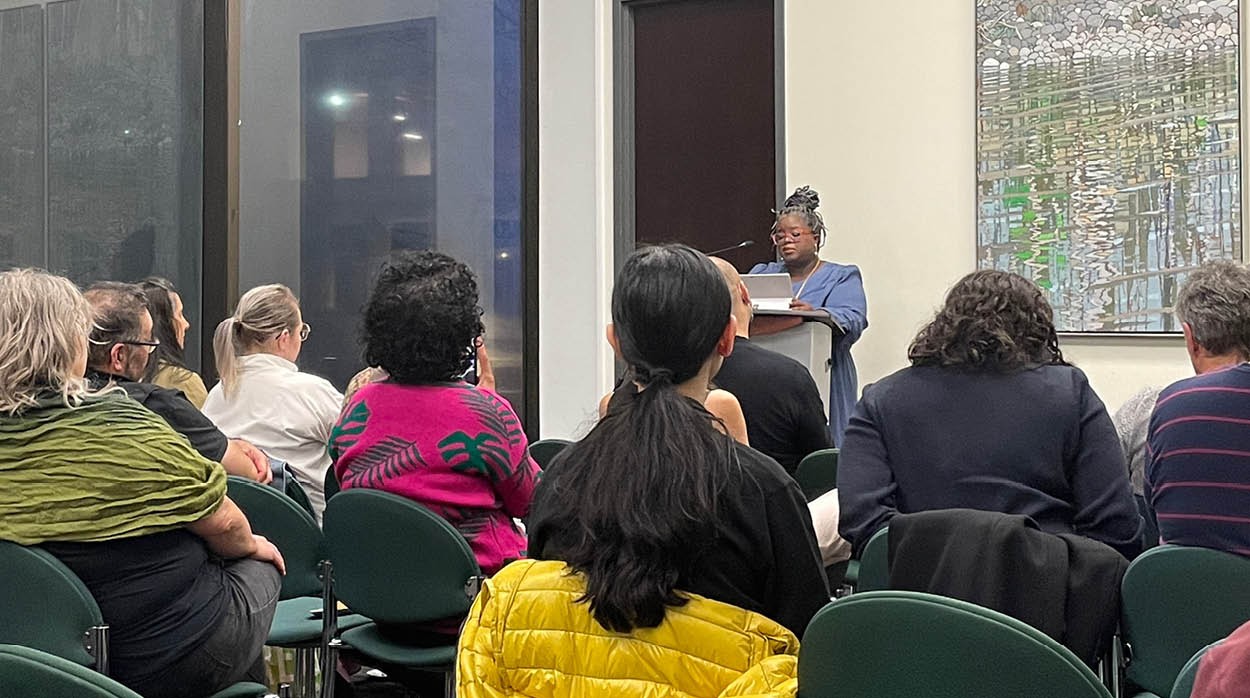 Junie Désil reading at a podium to an audience of people