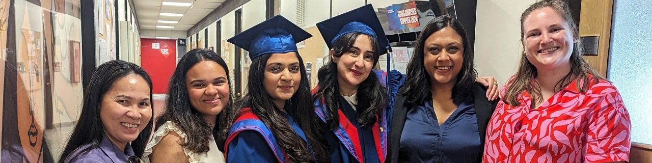 A group of GSWS graduate students, including two graduands in their regalia. 