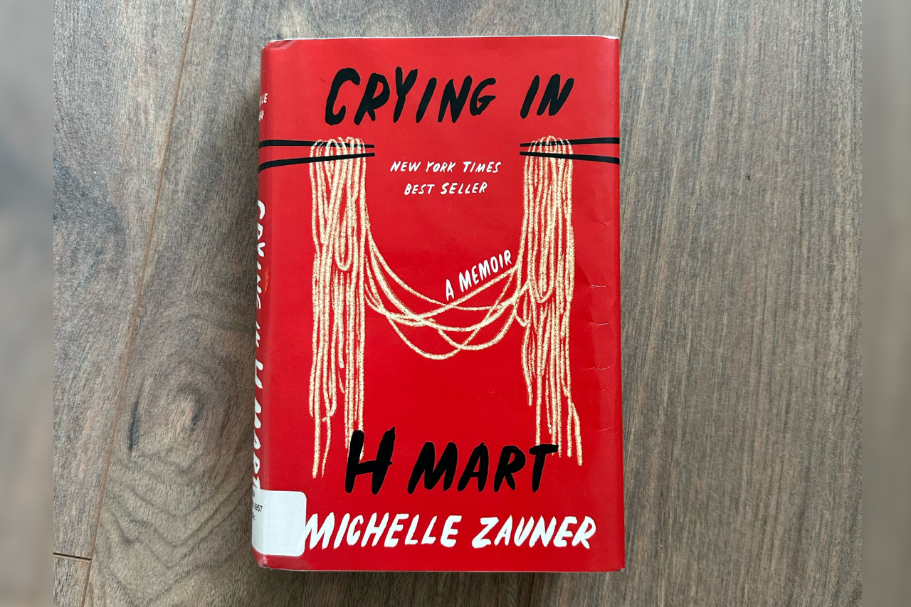 A copy of Crying in H-Mart by Michelle Zauner lying on a wood floor