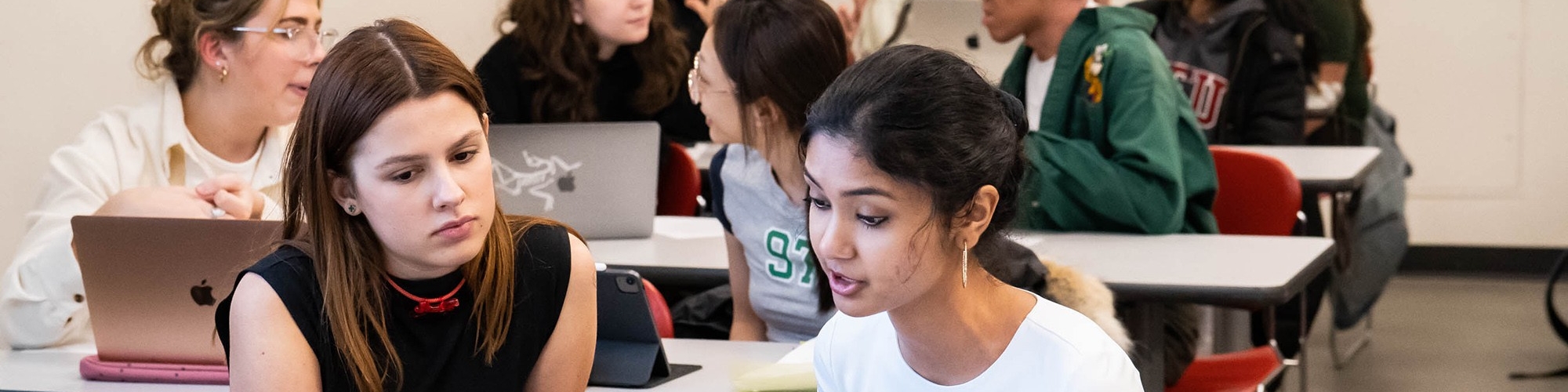 Students in GSWS 204 talking and looking at their laptops. 