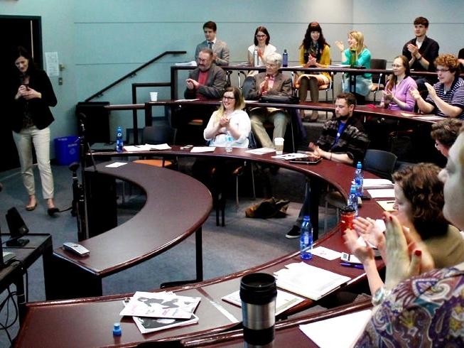 Students in the Emerging Leaders workshop sitting in a lecture hall, clapping for a speaker. 