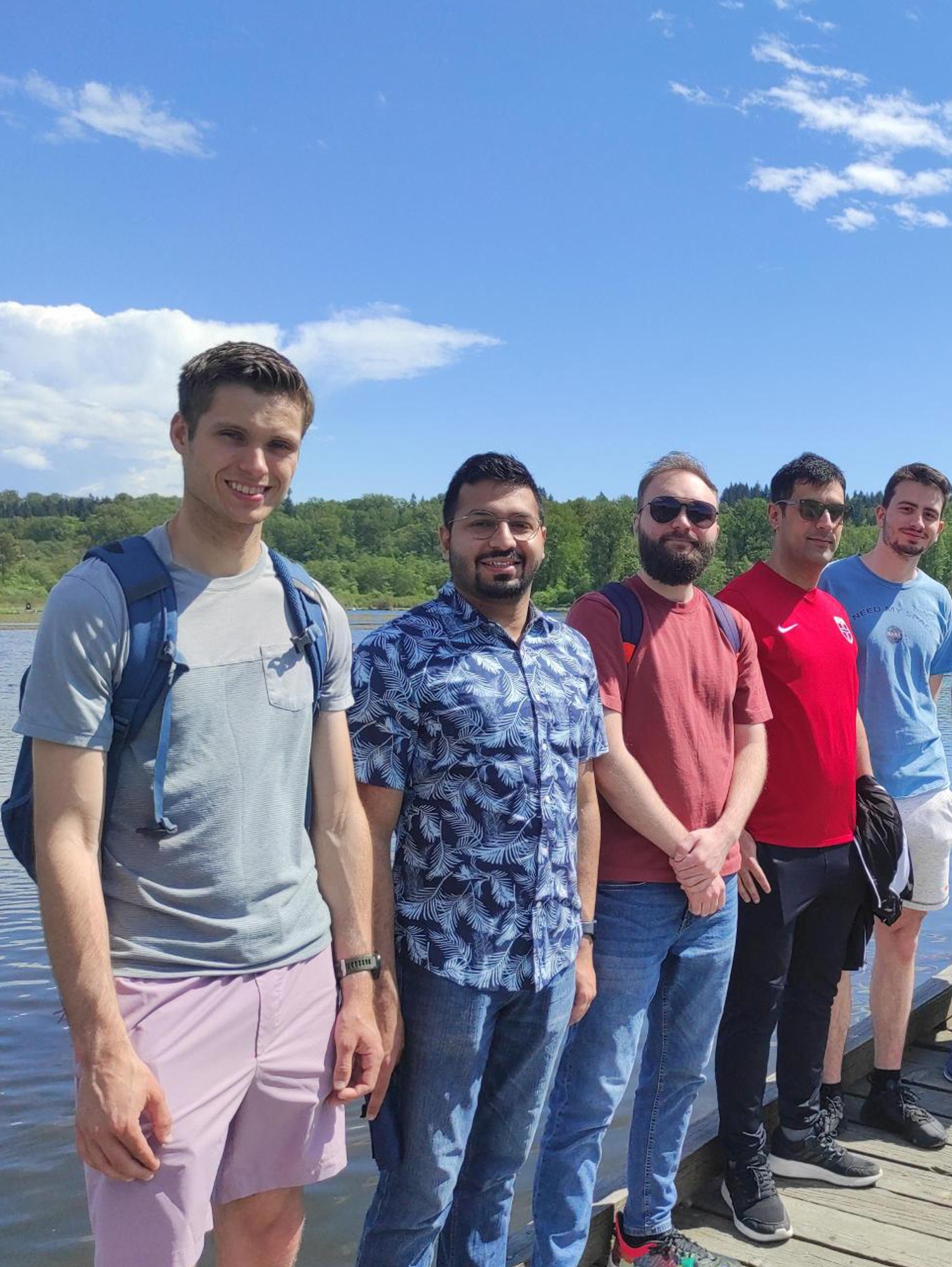 Graduate students from Hamilton Hall hanging out on the dock near a lake on a sunny day