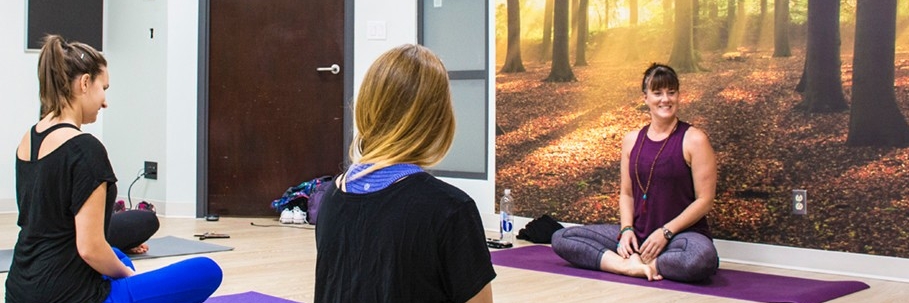 People practicing yoga against a wall with a mural in the SFU Vancouver Wellness Studio