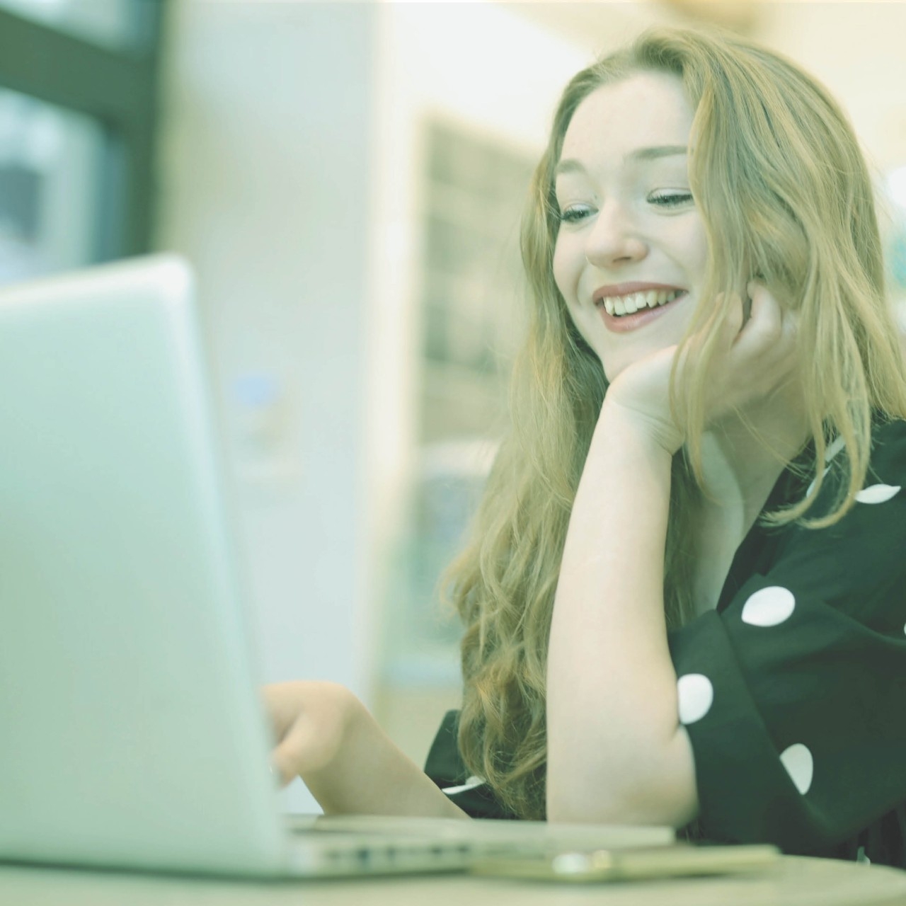 Person sitting and looking at laptop while smiling