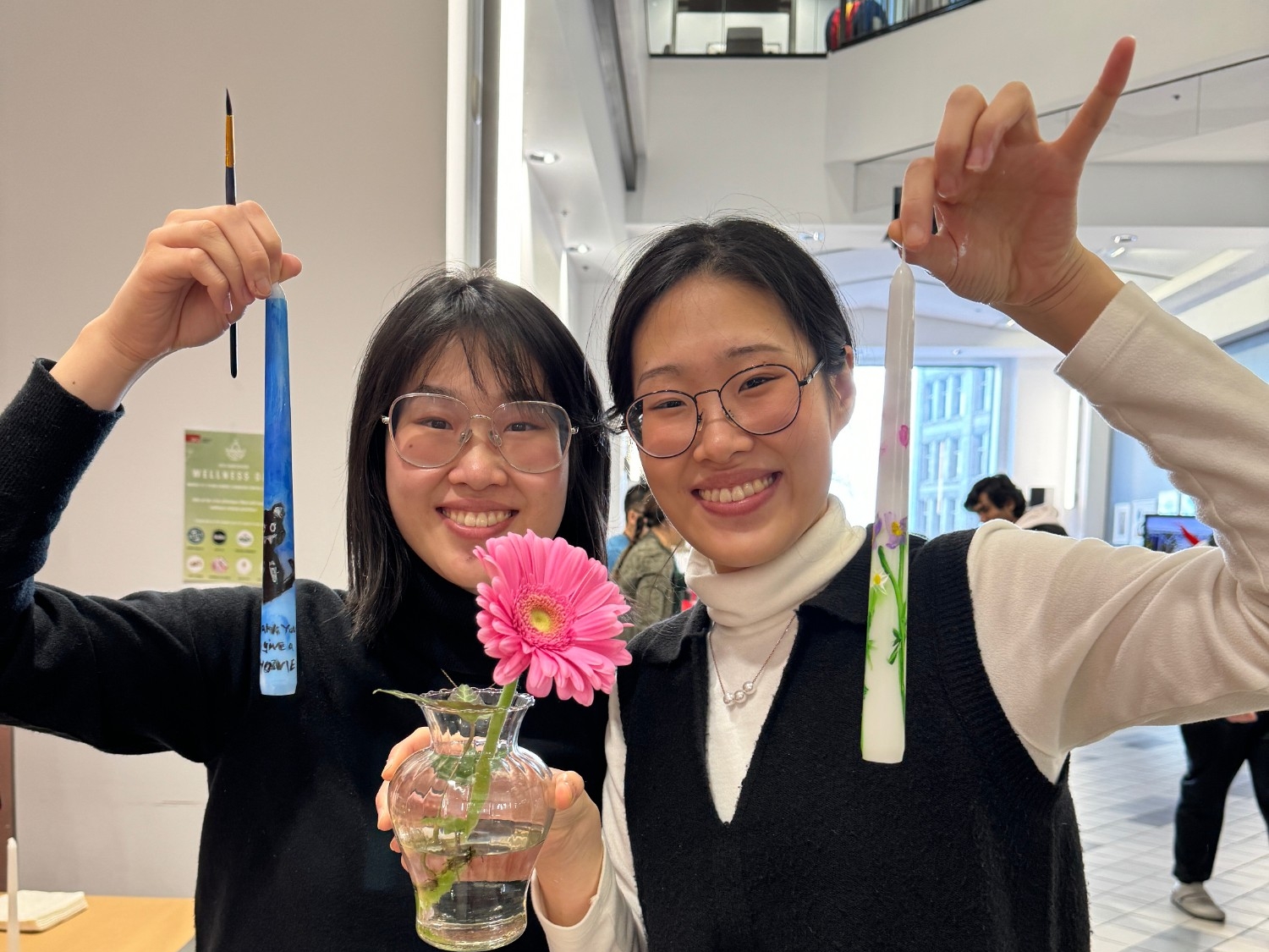 Two SFU Vancouver staff members holding up their freshly painted candles at Wellness Day 2024