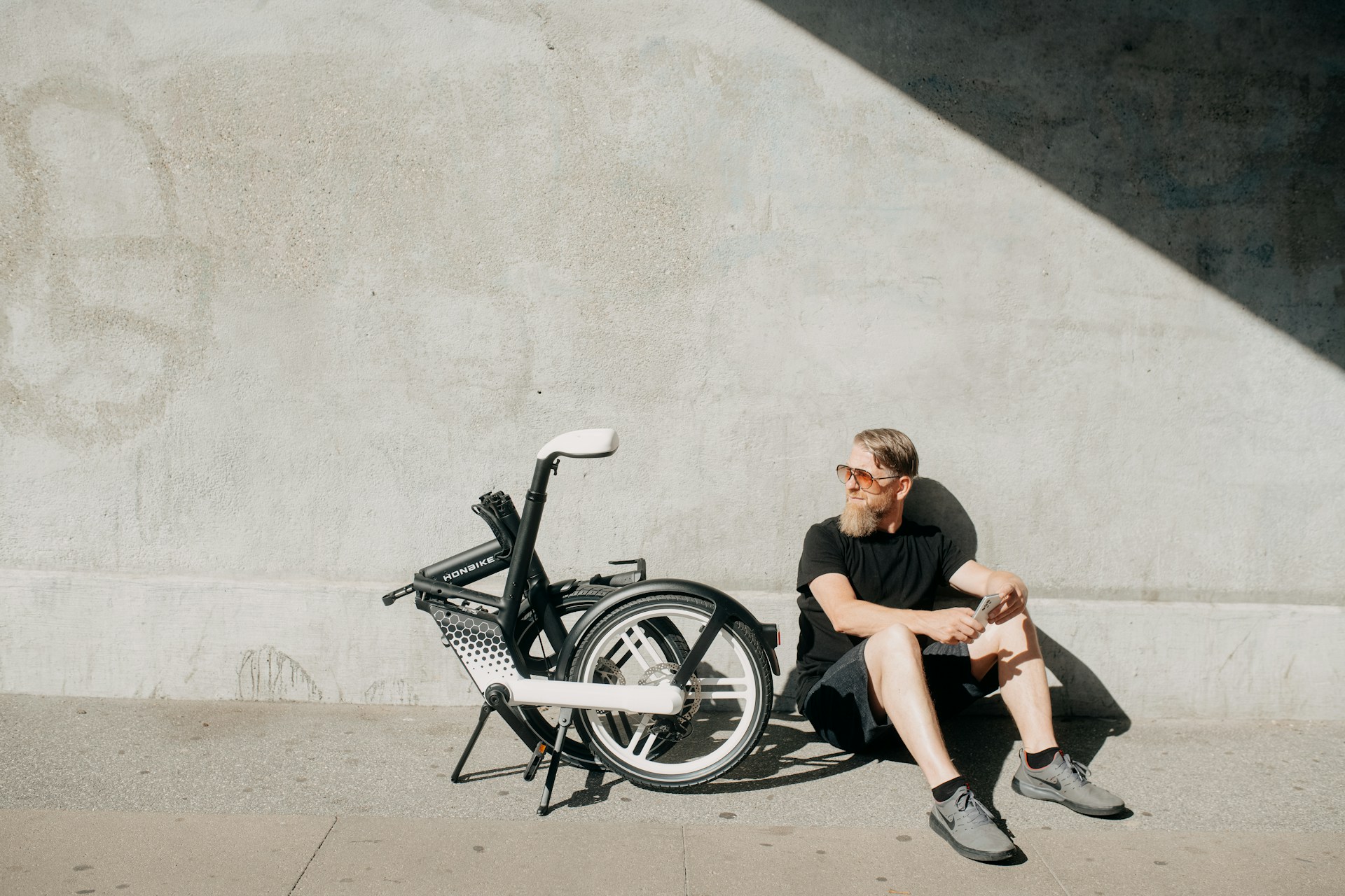 person sitting next to a bicycle in the sun