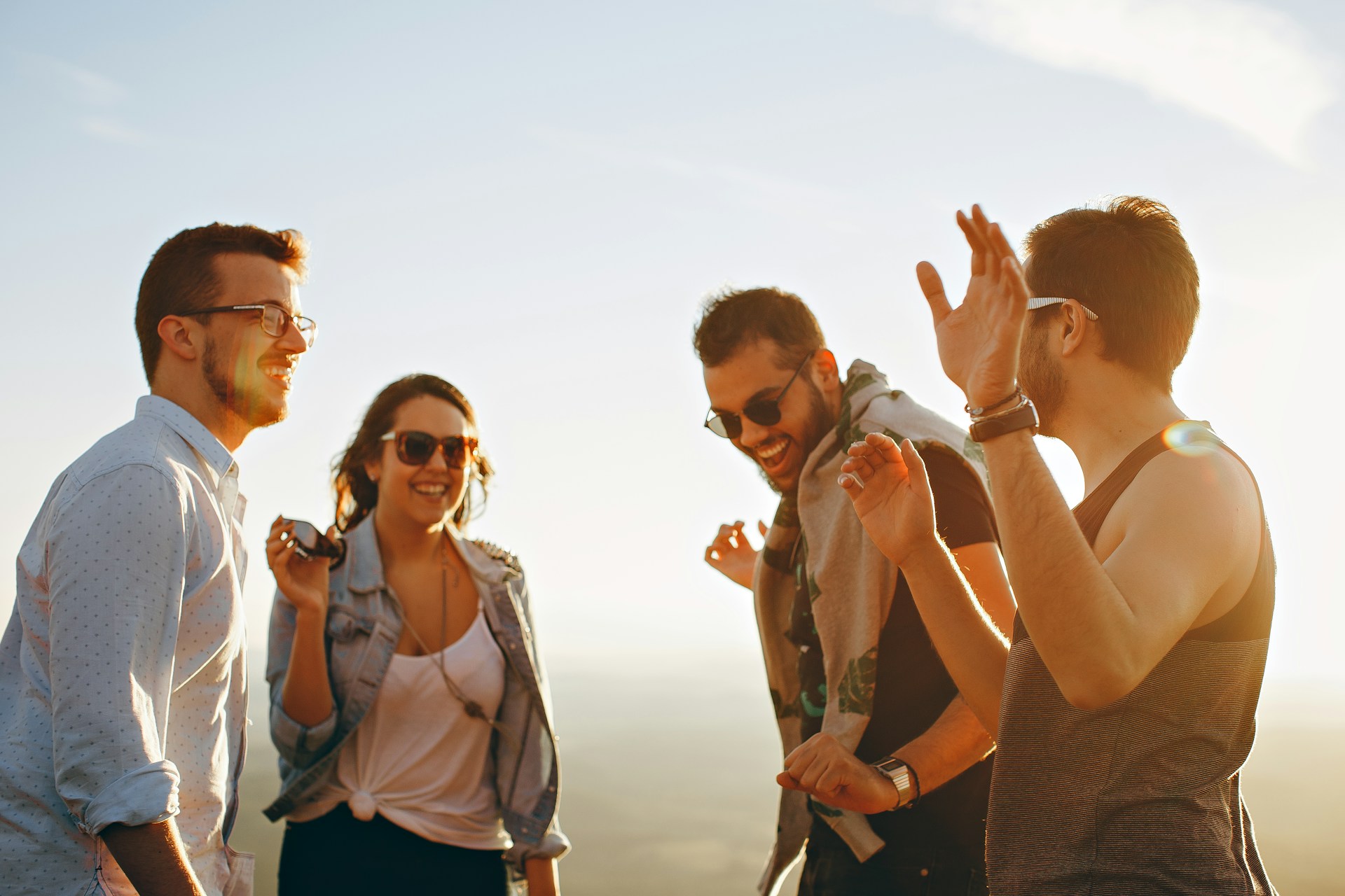 a group of people talking to each other and laughing under the sun