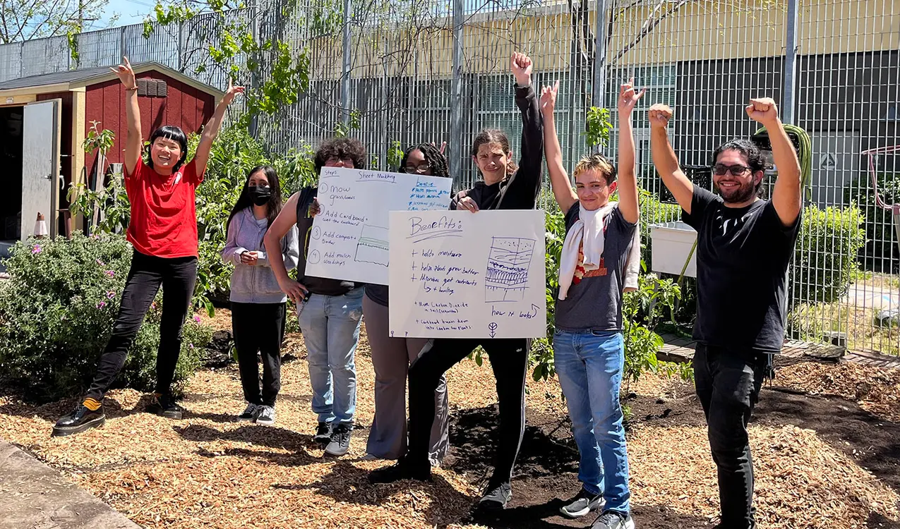 Group of peoplein a garden, holding posters about gardening benefits.