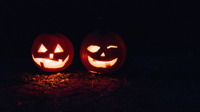 an image of two lit jack o' lanterns in the dark.