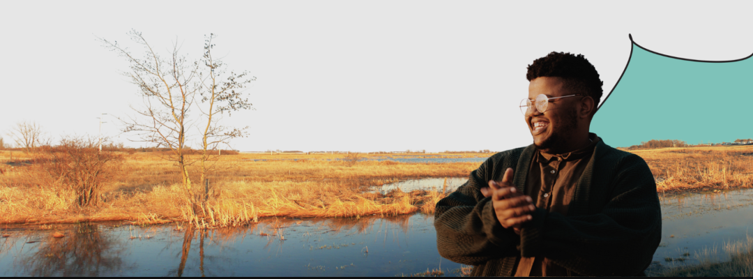 A smiling man clapping his hands while in front of a marsh