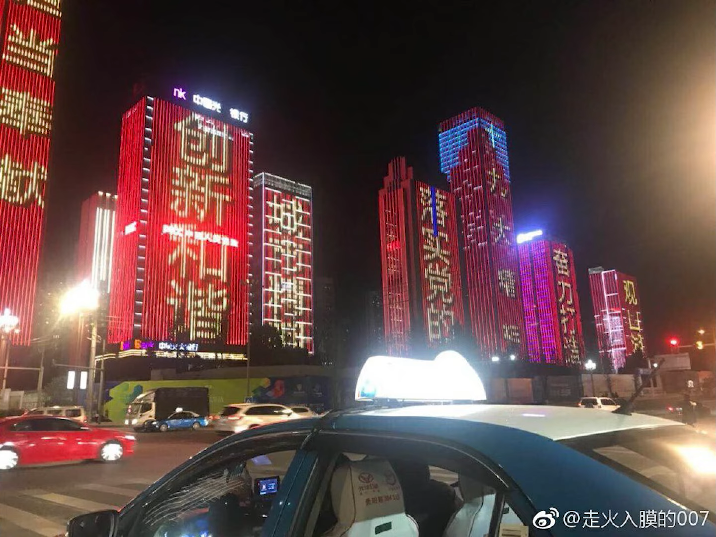 fourth posted image, showing a night scene where a series of buildings have propaganda slogans being displayed on their LED wall. all buildings are covered with bright red LED, which creates a creppy visual effect against the night sky.