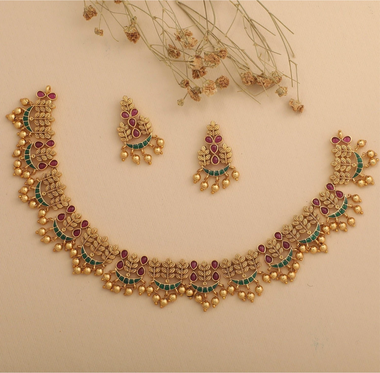 a matching gold necklace and earring set with ruby gems