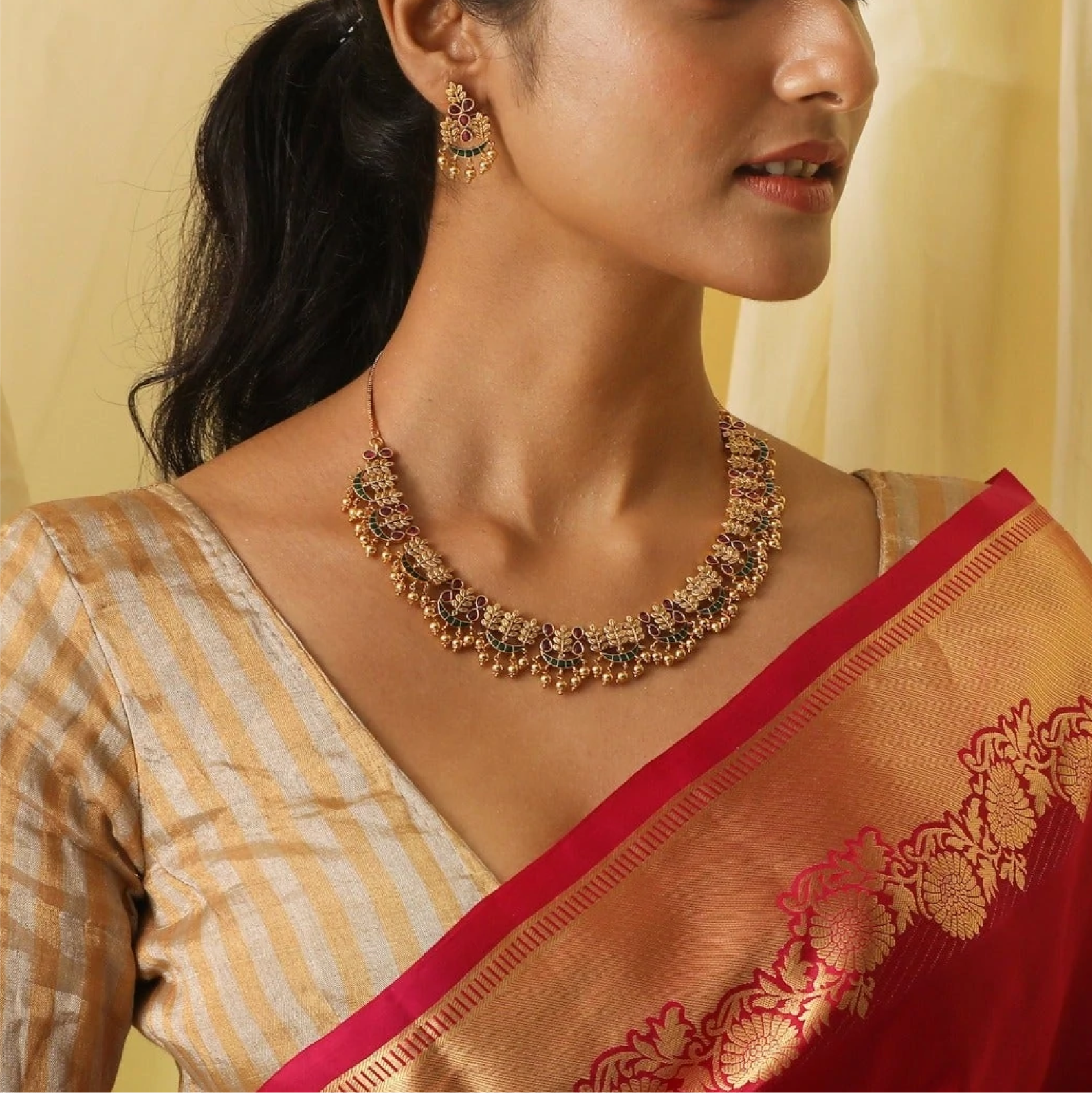 model wearing a matching gold necklace and earring set with ruby gems