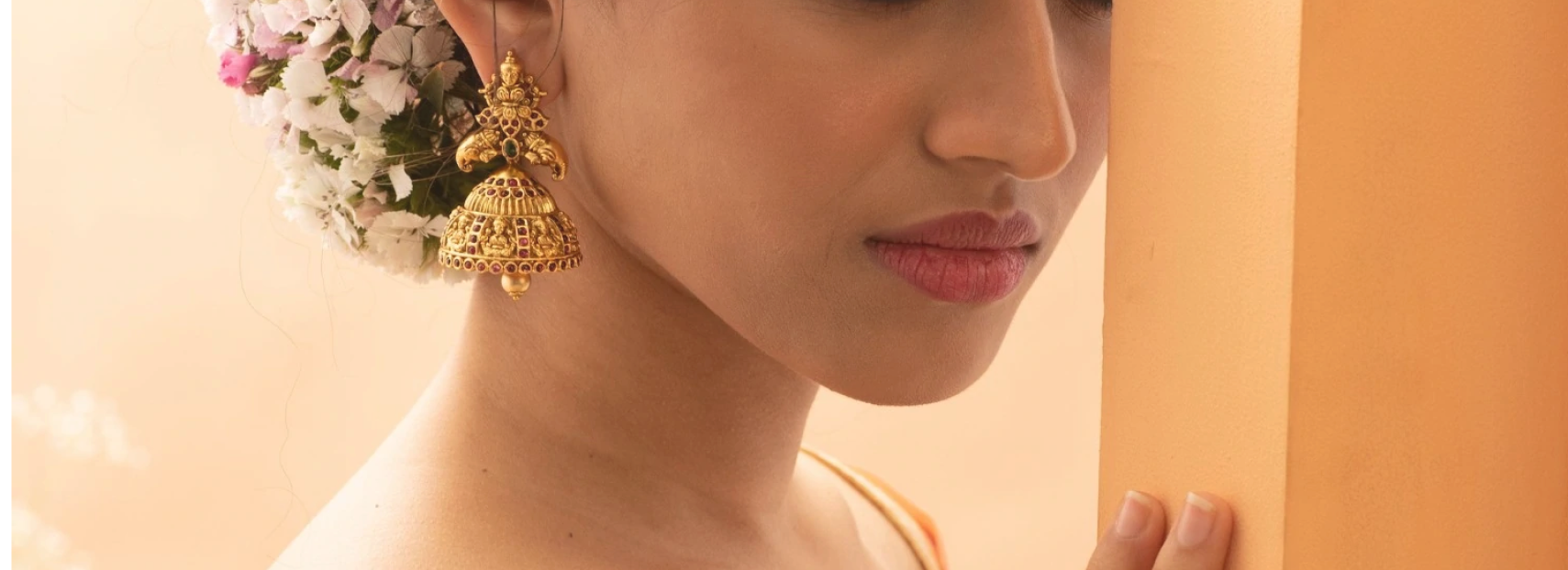 model wearing golden jhumka earrings with emerald and ruby gems