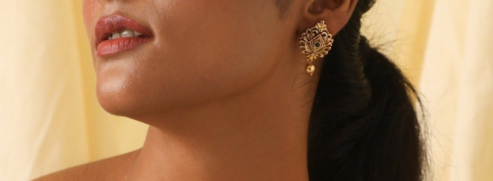 model wearing golden stud earrings with a diamond center and dangling ball