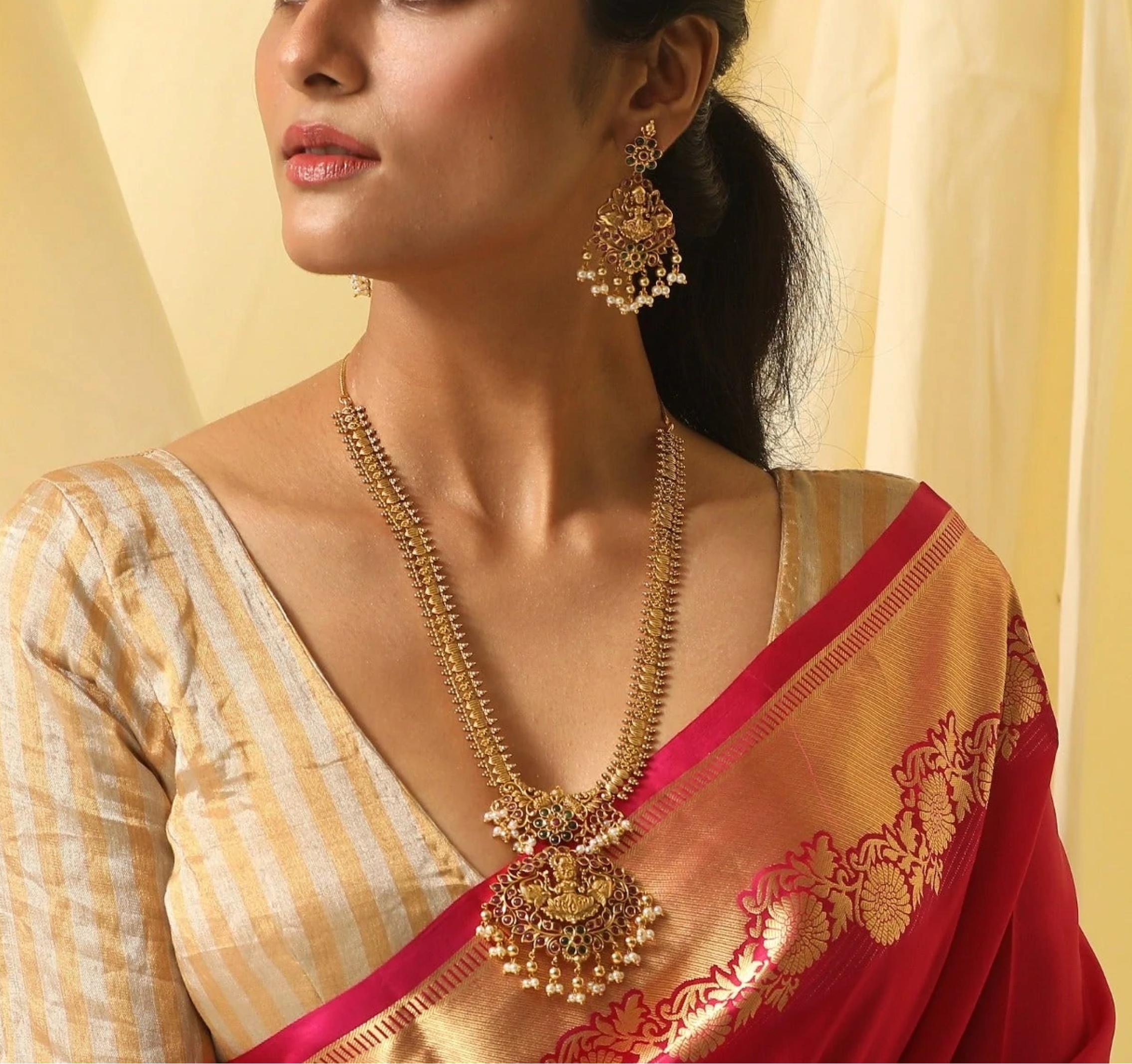 model wearing a matching long gold necklace and earrings with pearls