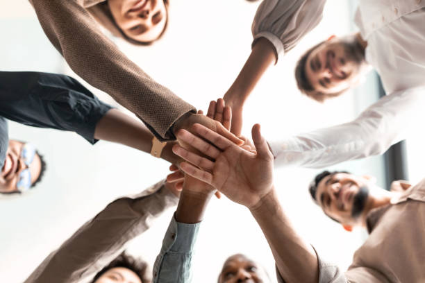 A group of people all huddling with their hands in the center