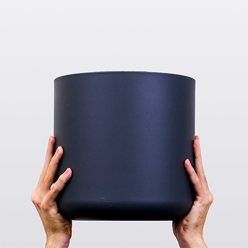 Hands holding a large black plant pot