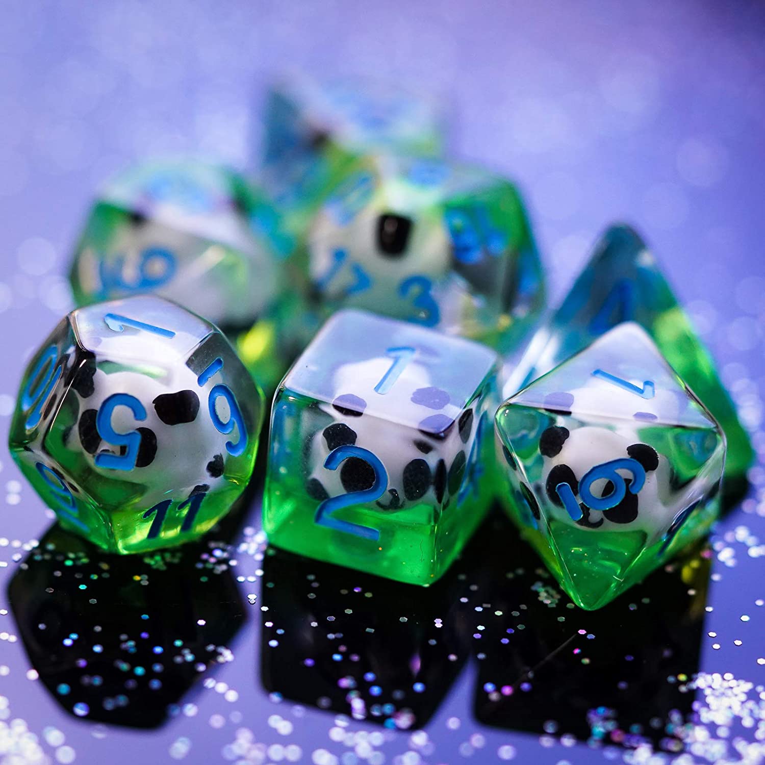 7 Translucent resin dice with a panda figure inside on a glittering surface