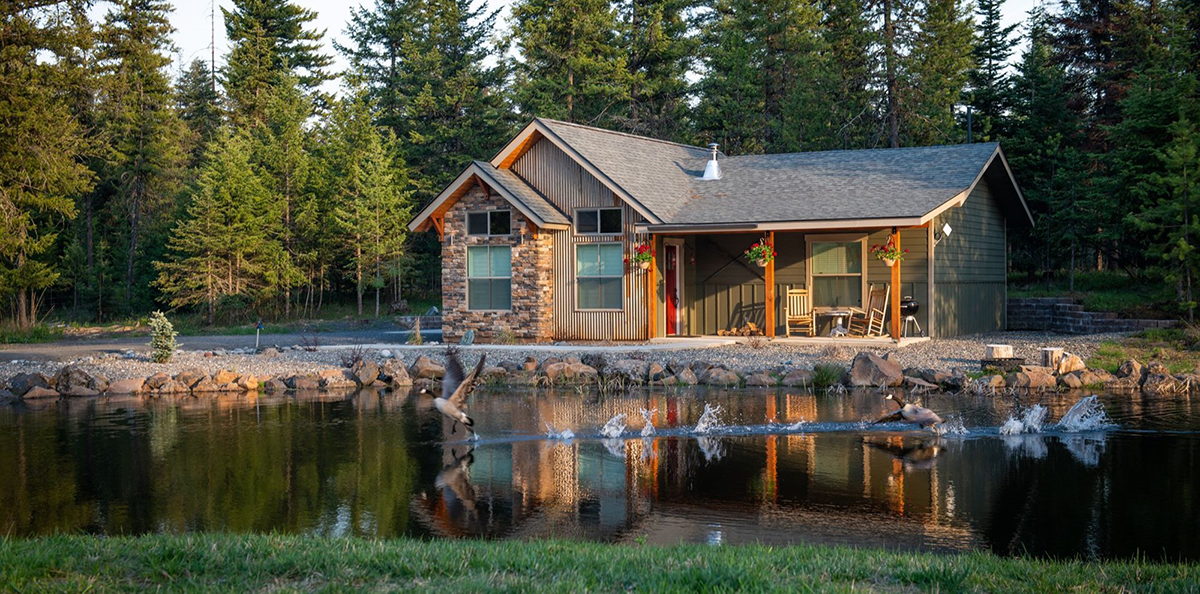 a log cabin behind a lake
