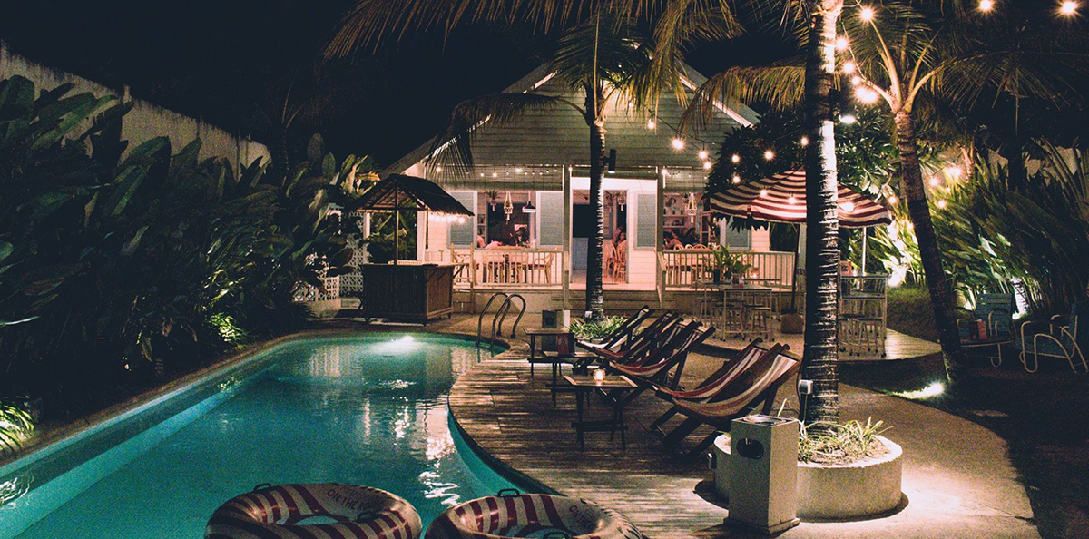 A backyard pool lit up with string lights at night