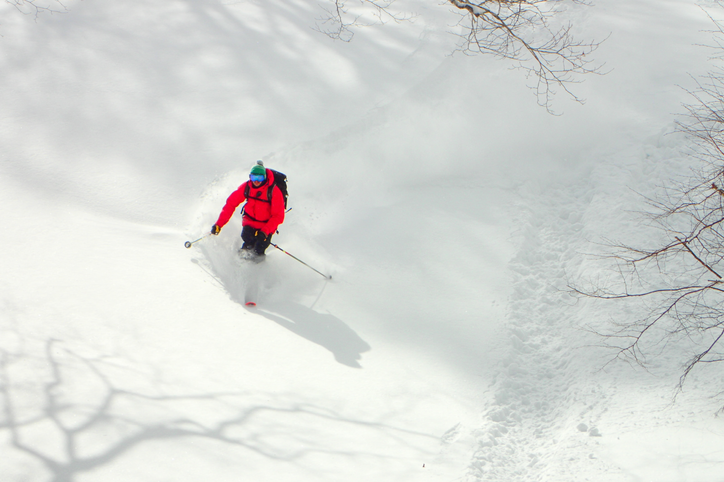 red jacket skiier skiing down white powder snow