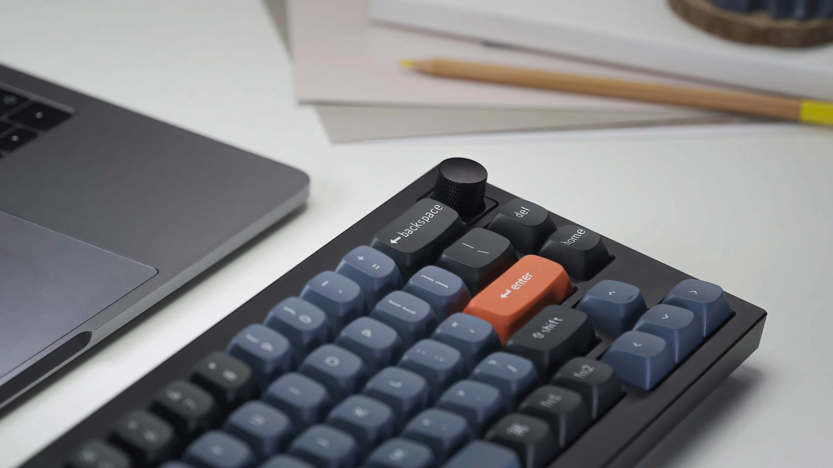 a close-up of CantoKey Dennis V2 beside an macbook on a desk