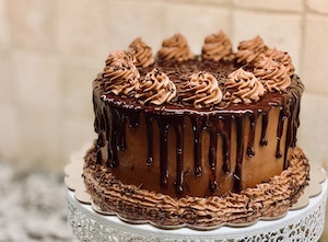 a chocolate cake dribbled with chocolate sauce and piped with swirly frosting