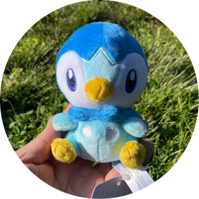 Review image of Sitting Cuties Piplup plush sitting on person's hand against the grass.