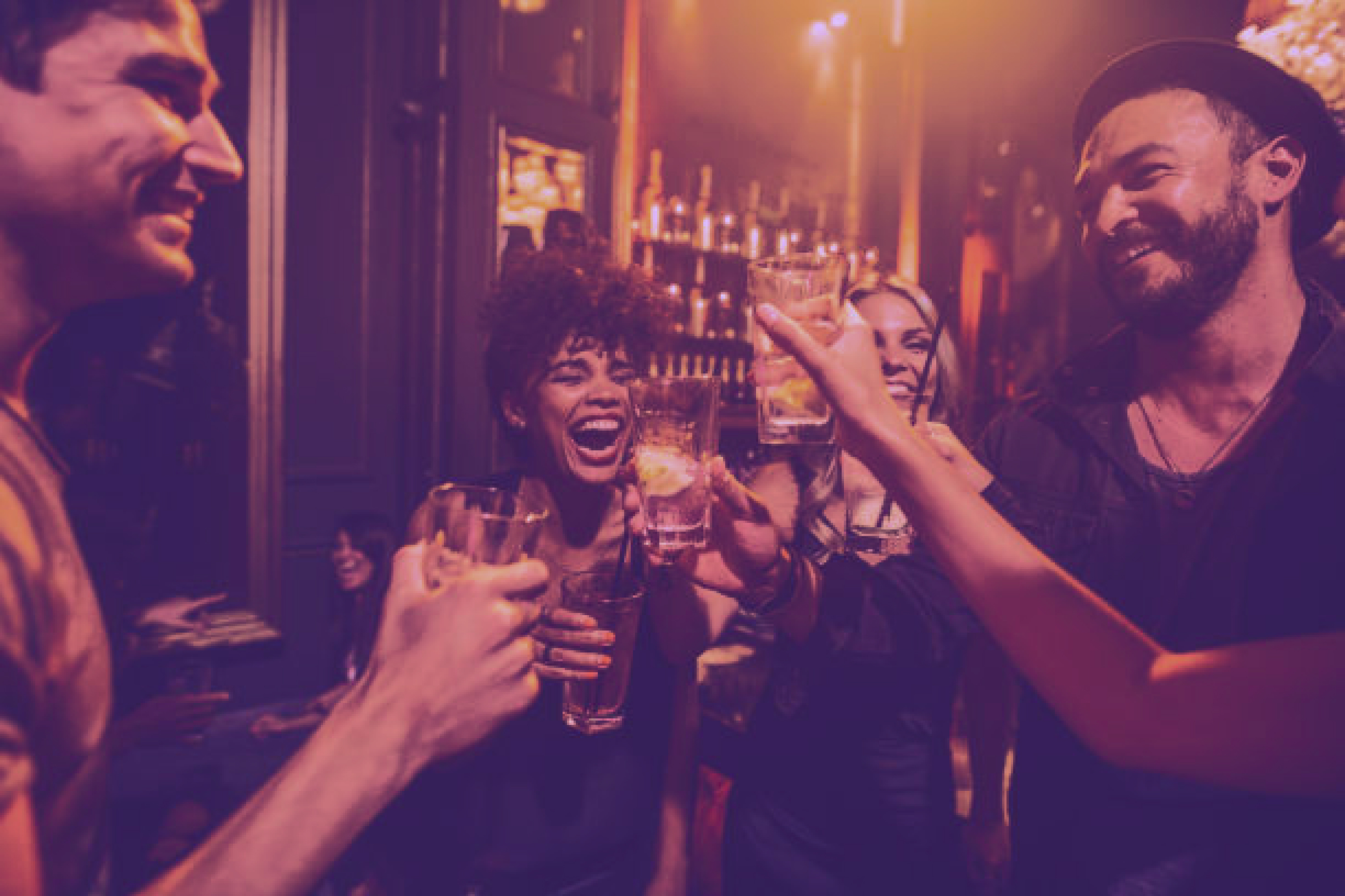 a group of young adults toasting at a bar