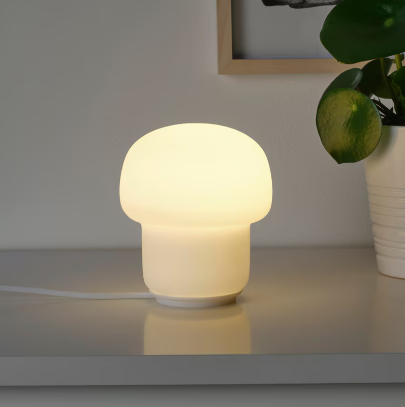 Small white lamp with warm light somewhat resembling a mushroom.