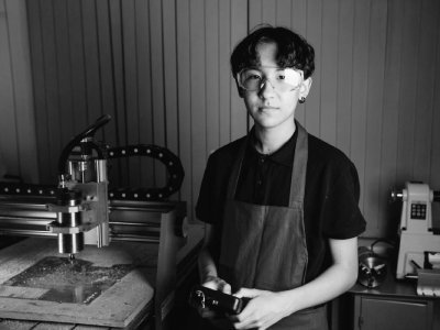 Young man next to a cnc machine.