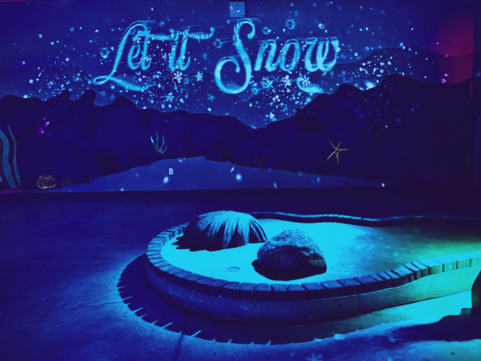 a winter themed minigolf course with a 'let it snow' glowing sign