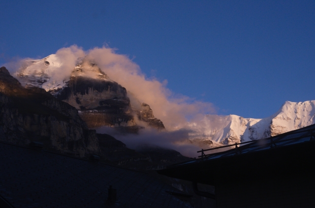 A snow-capped mountain wrapped in a cloud in the sunset