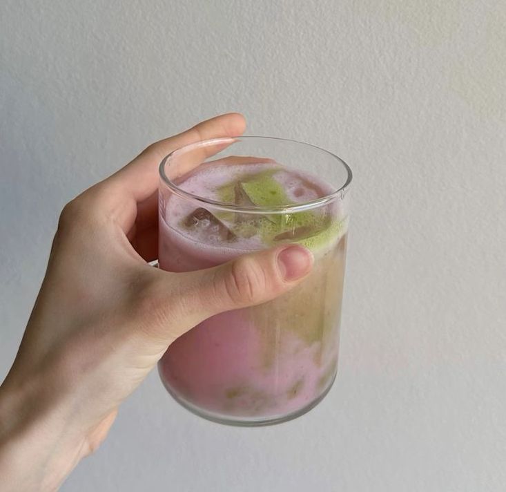 a review image of someone holding a glass of strawberry matcha drink